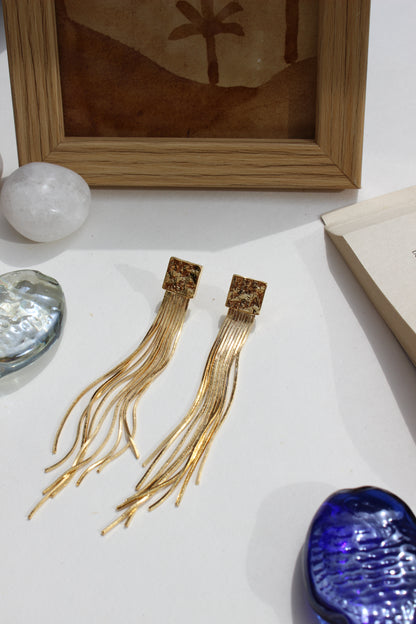 Soft Steel Earrings on a white surface with a wooden frame and decorative stones
