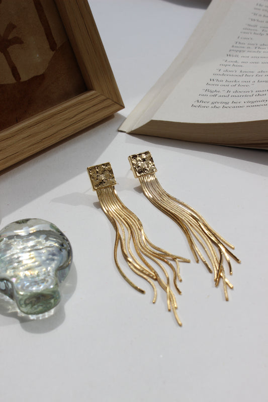 Soft Steel Earrings bookmarks on an open book with a crystal seashell in the background