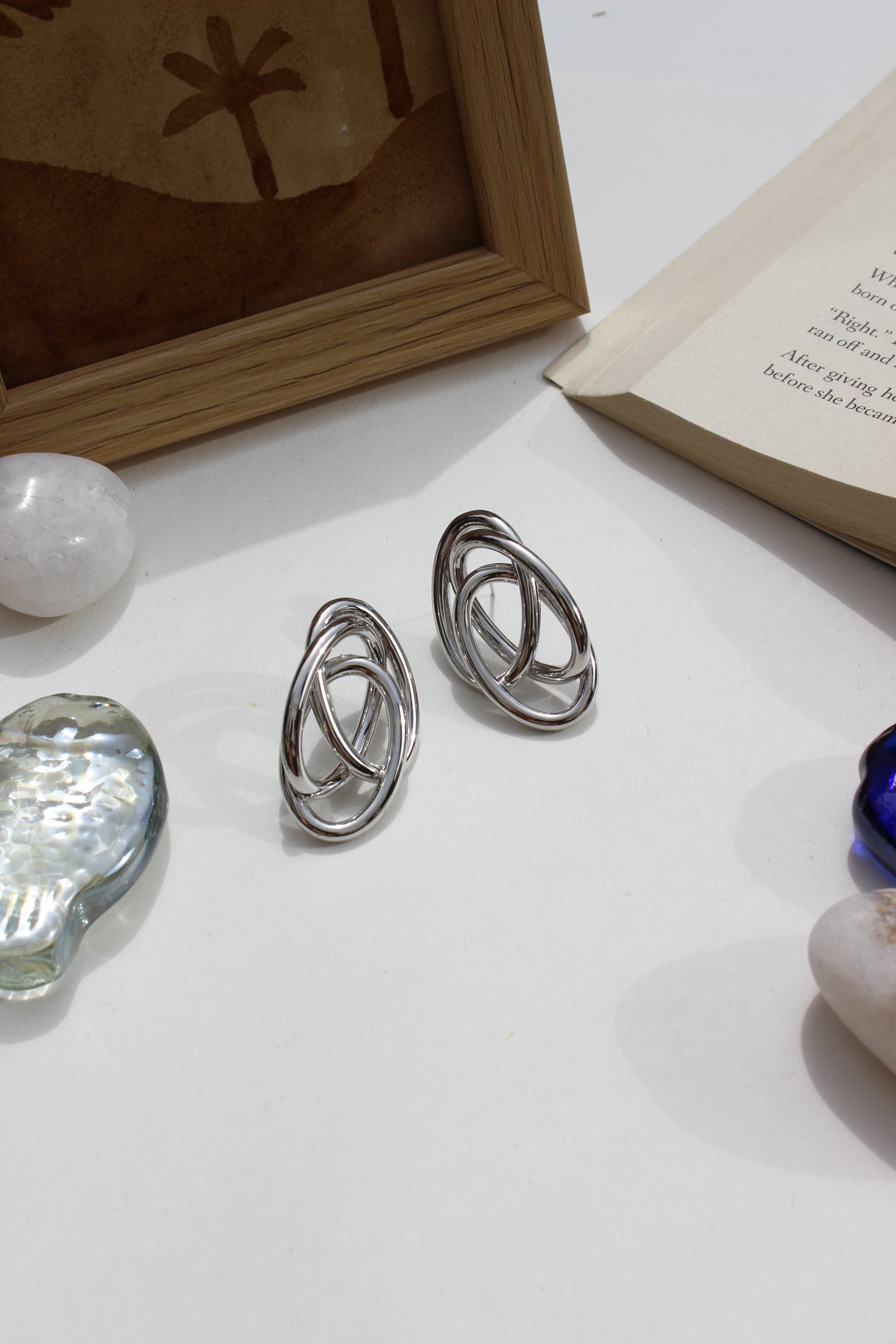 Silver Orbit Earrings on a white surface with a blurred background