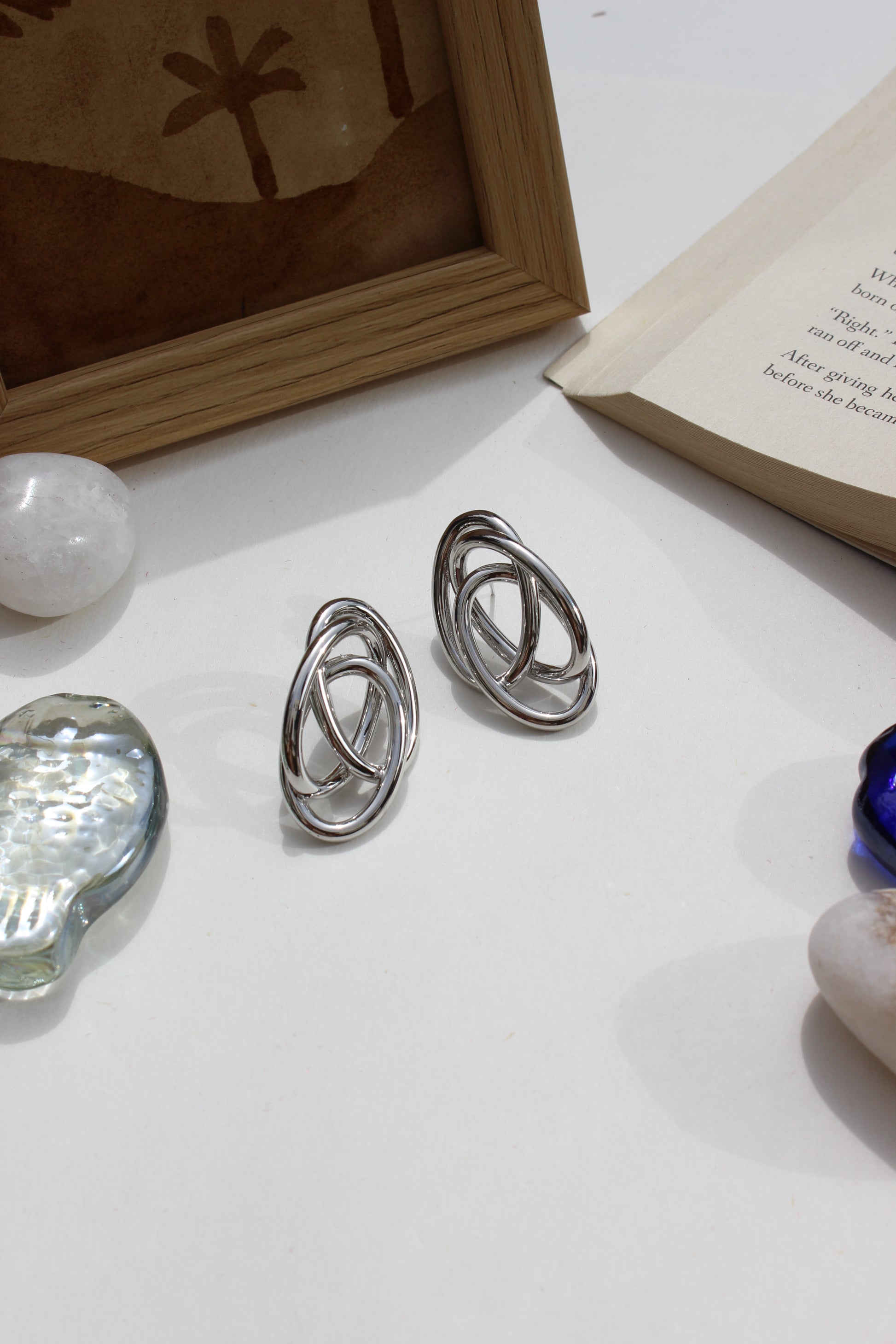 Silver Orbit Earrings on a white surface with a blurred background