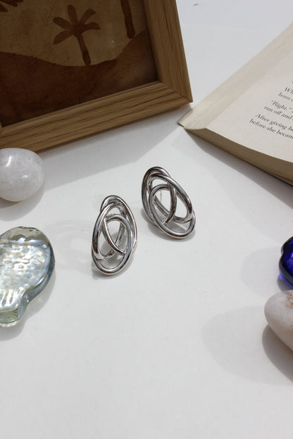 Silver Orbit Earrings on a white surface with a blurred background