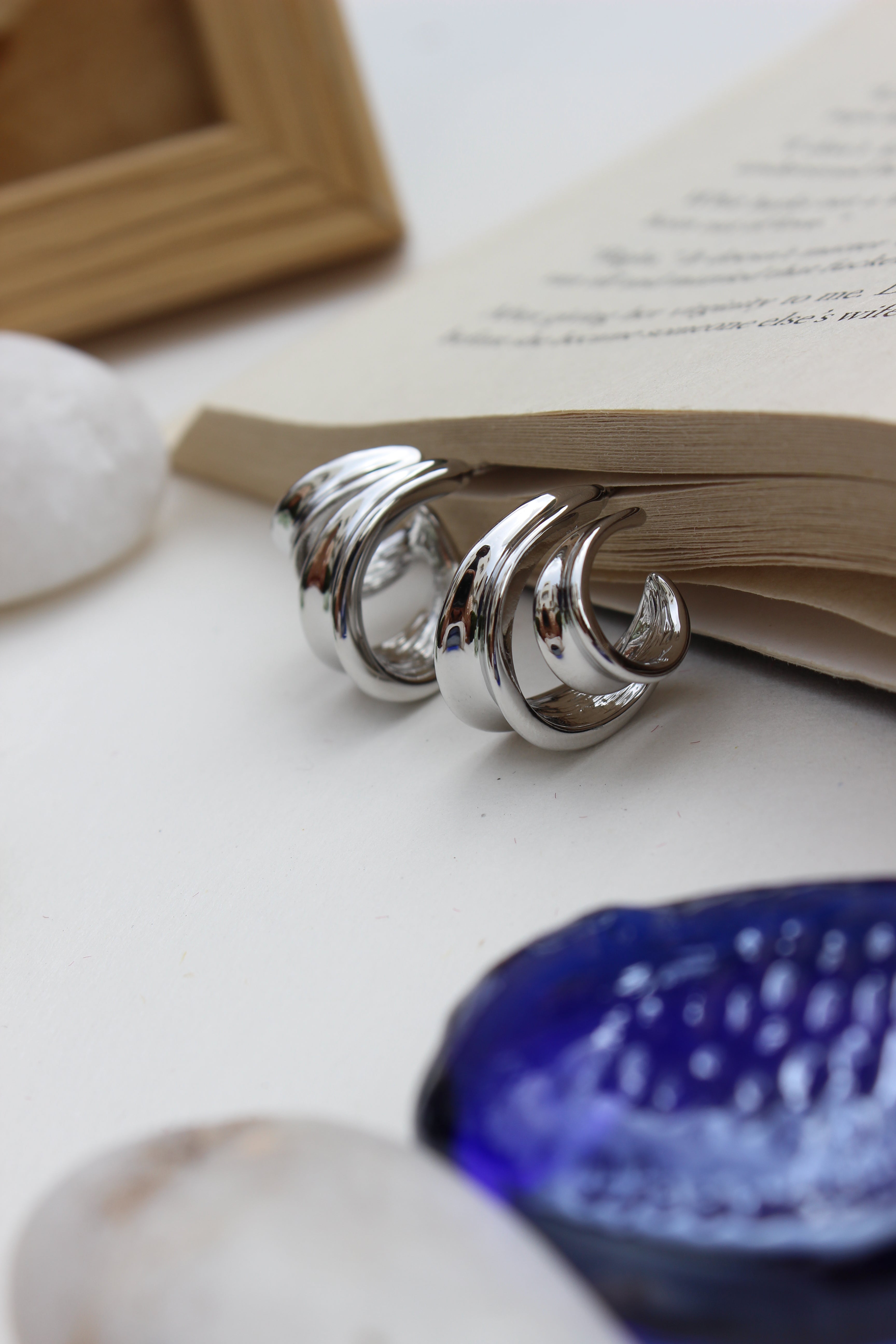 Winter Hug Earrings on open book pages with sea shells, white background, elegant seasonal jewellery for women in India
