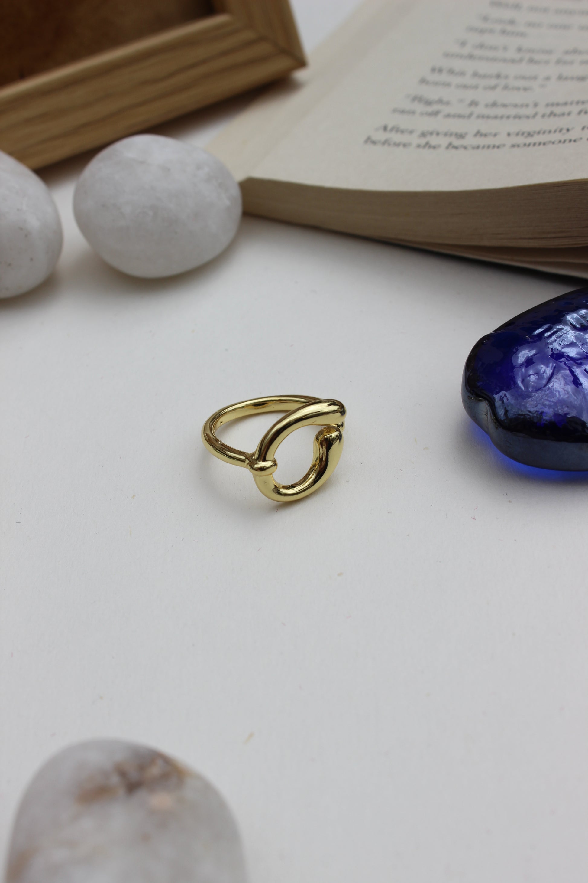 Warm Loop Ring on a white surface with a blue seashell and book in the background