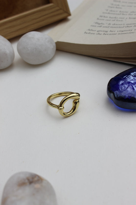 Warm Loop Ring on a white surface with a blue seashell and book in the background