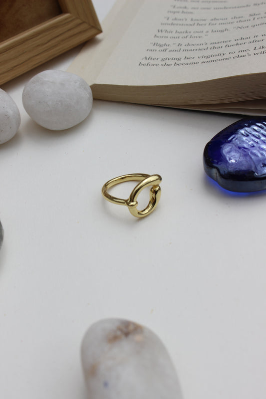 Warm Loop Ring on a white surface with book and stones