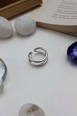 Brushed Moon Ring on a surface with stones and a book