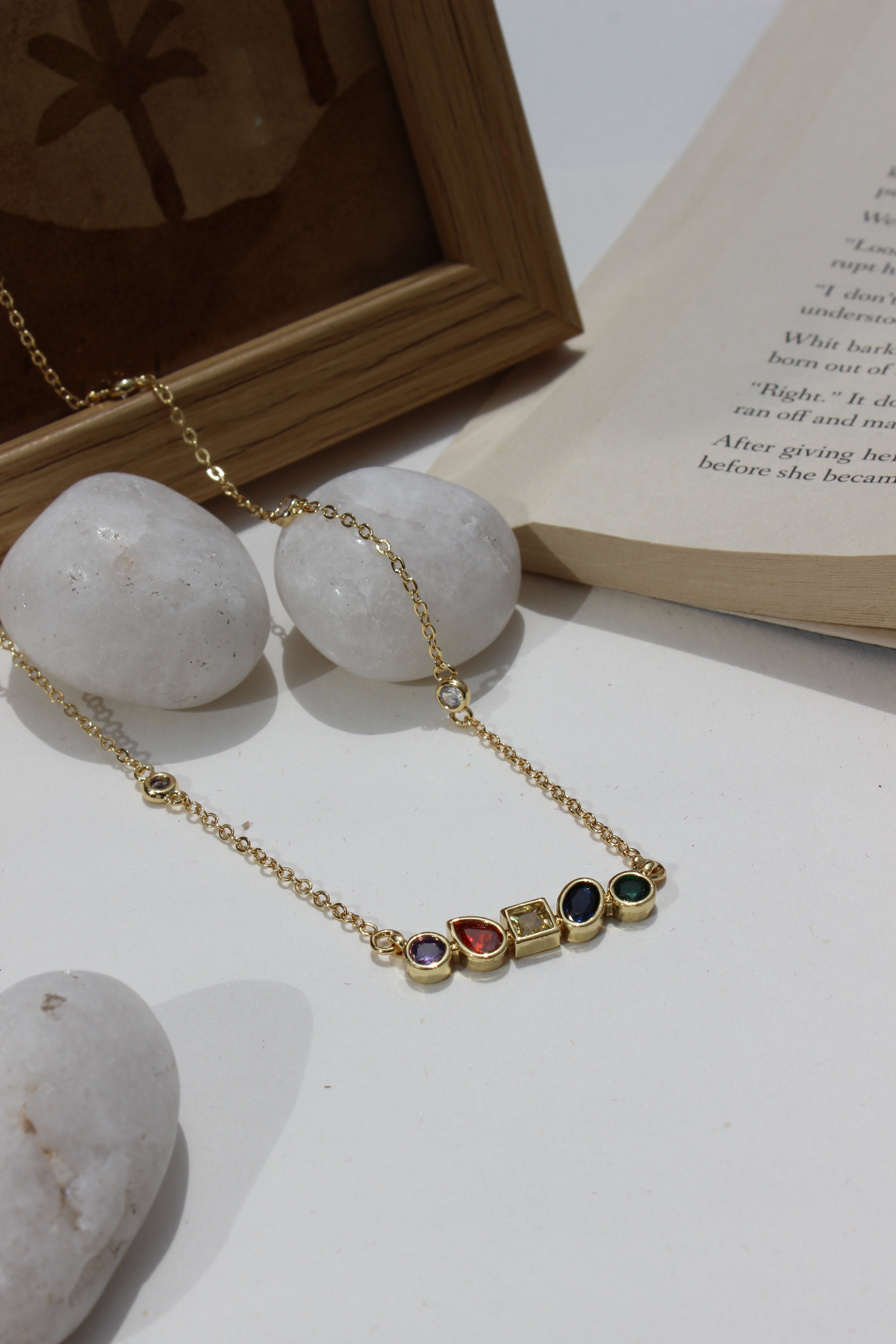 Carry Light Pendant Necklace on a white surface next to an open book