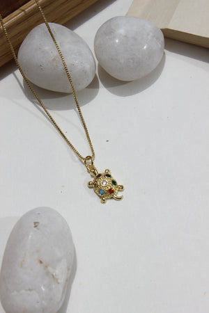 Luck Shell Pendant Necklace on a white surface with stones and wooden frame