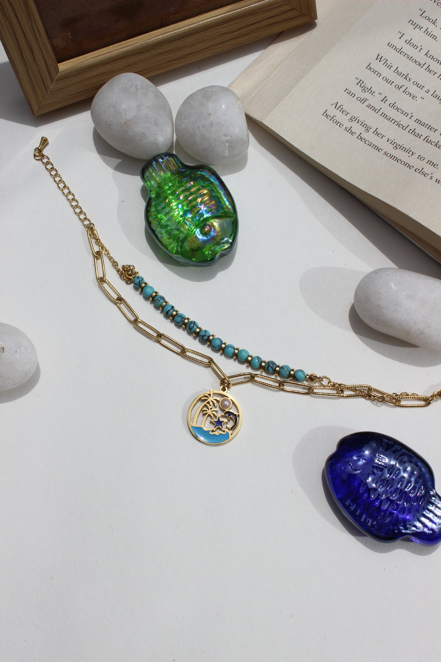 Ocelette Layered Bracelet on a white surface with stones and books