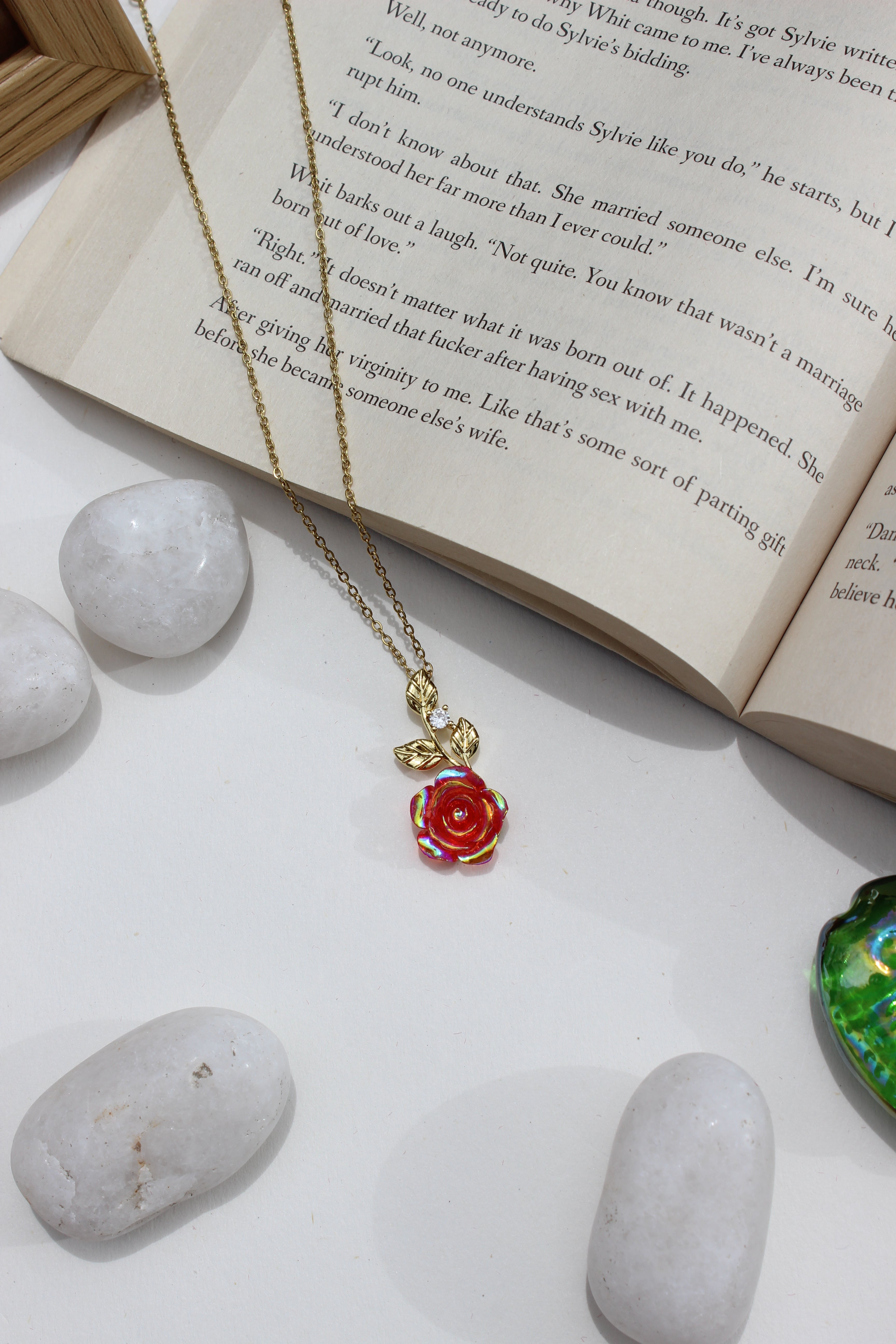 Primrose Dawn Pendant Necklace on an open book with stones around