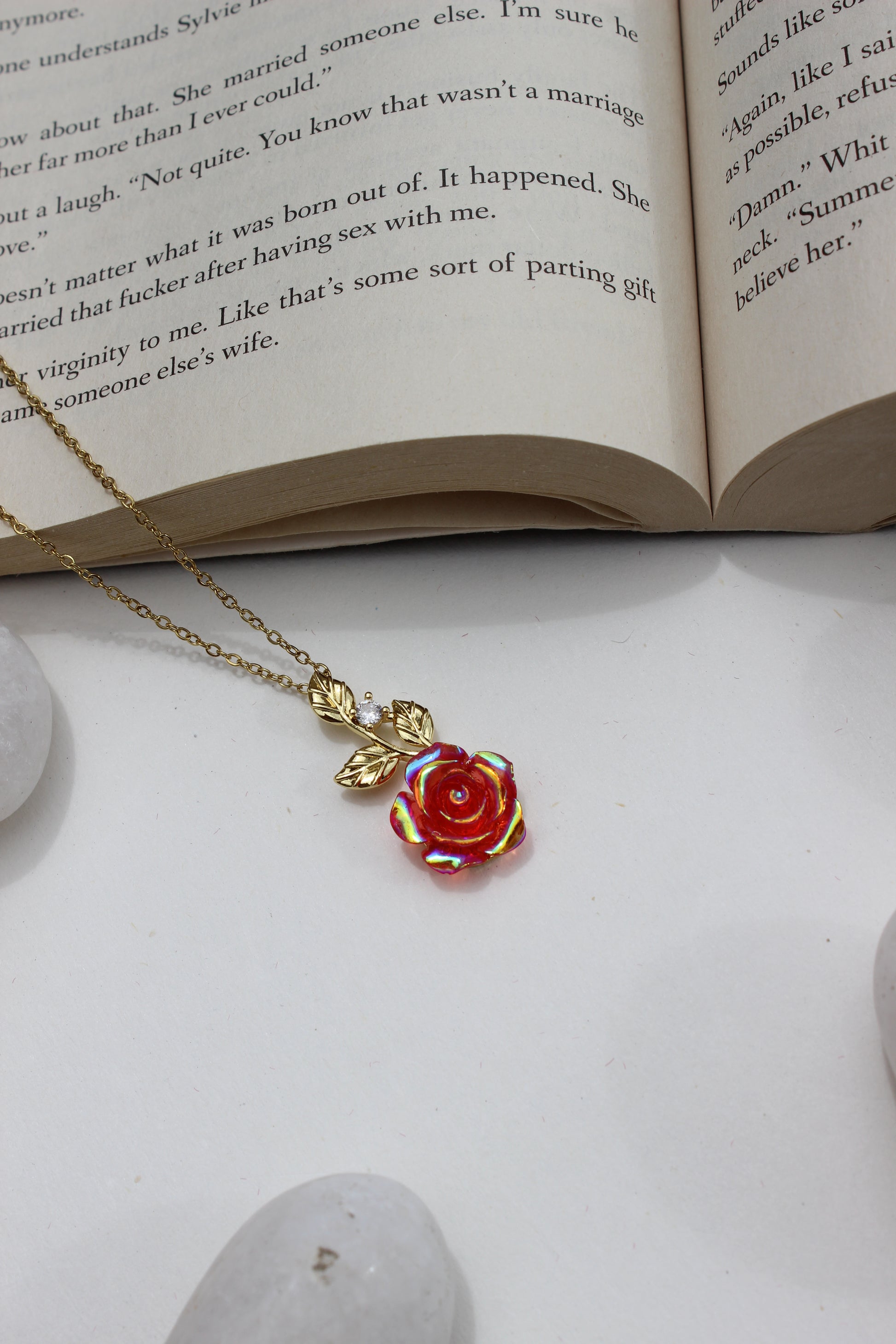 Primrose Dawn Pendant Necklace on an open book with a stone surface underneath