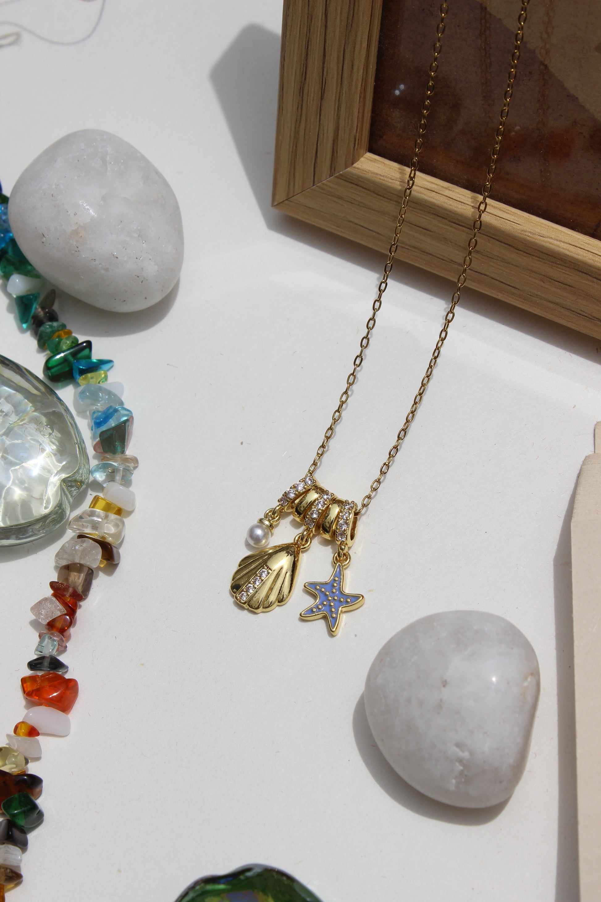 Mermaid Keepsake Charms Pendant Necklace on a white surface with stones and beads
