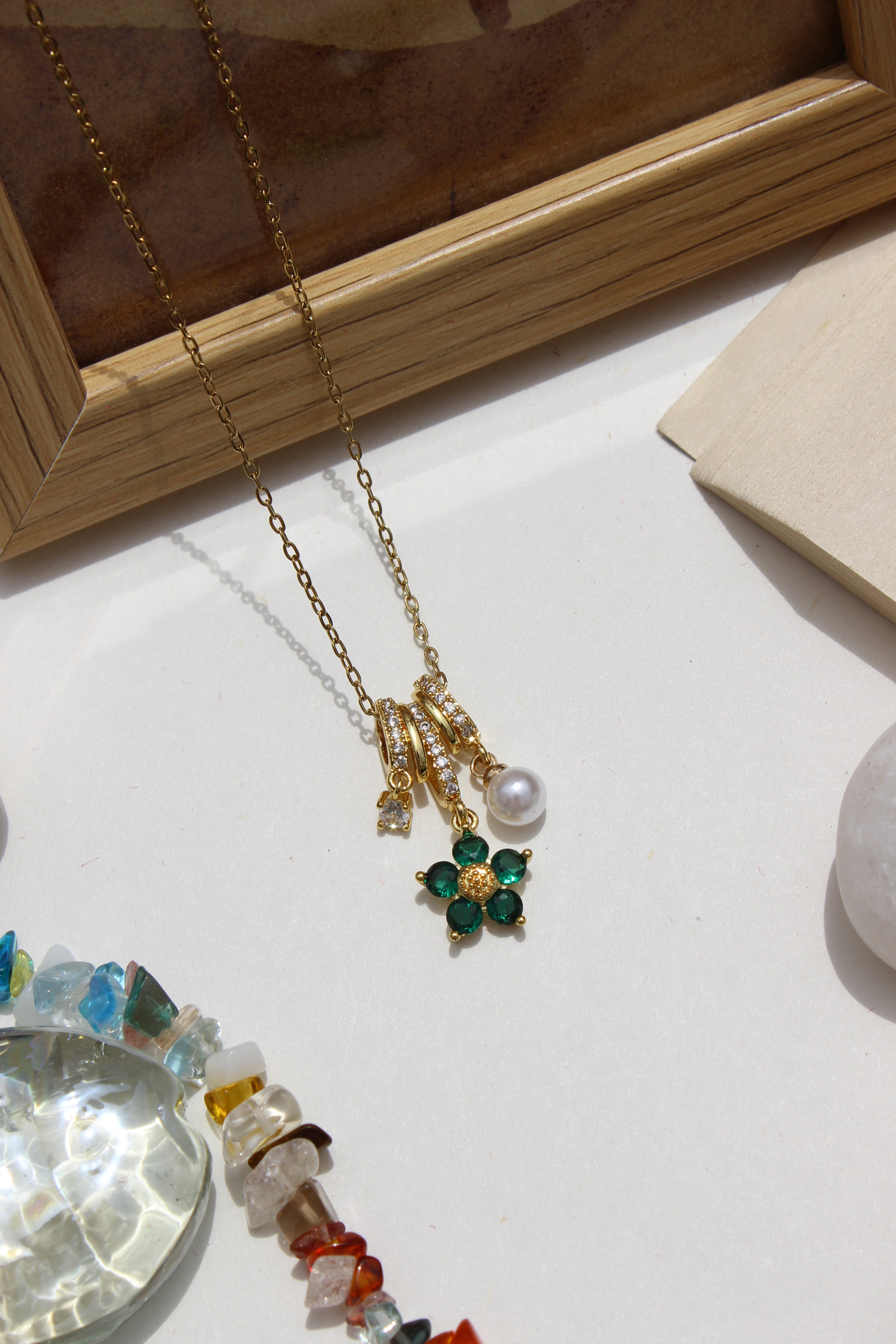 Lustre Garden Charms Pendant Necklace on a light surface with a wooden frame