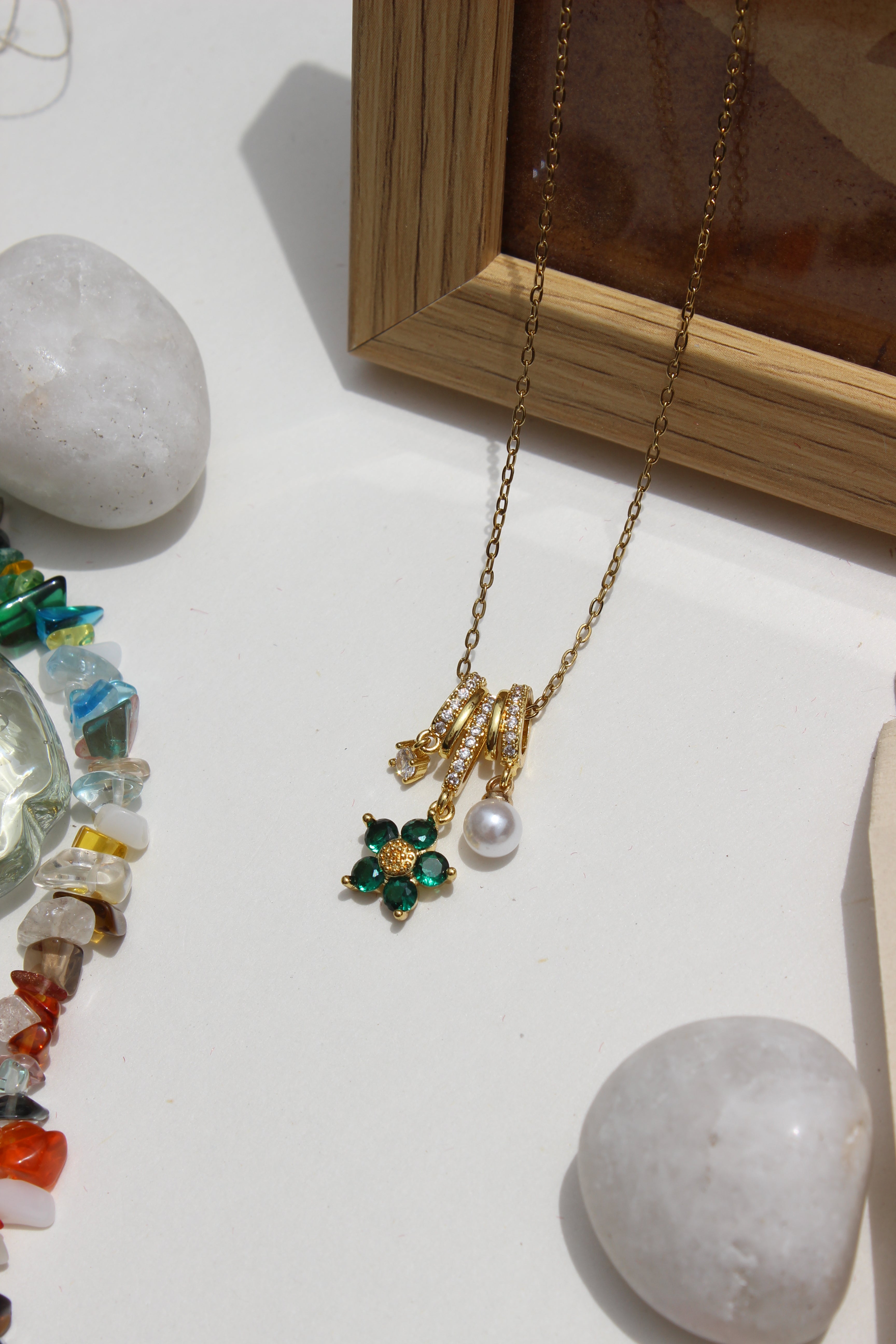 Lustre Garden Charms Pendant Necklace on a white surface with stones