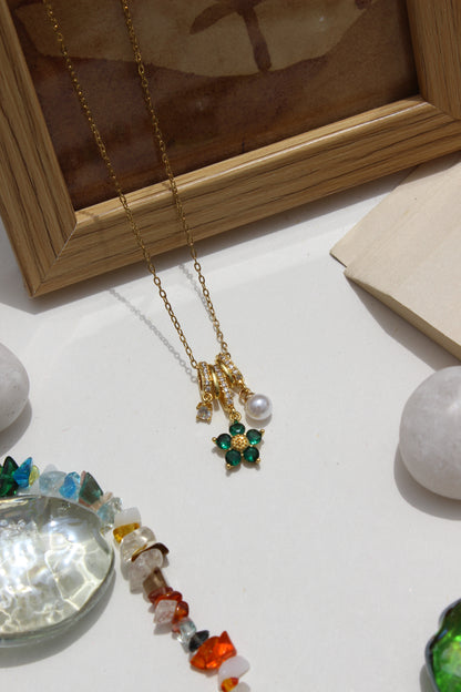 Lustre Garden Charms Pendant Necklace on a light surface with a wooden frame and crystal ball in the background