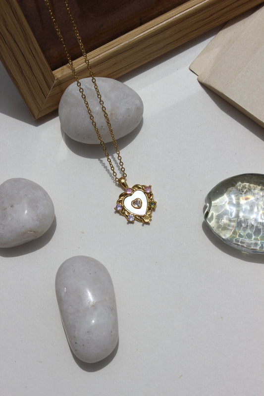 Everglow Heart Pendant Necklace on a white surface with rocks 