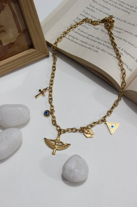 Eye of Gold Charms Necklace on a light surface next to an open book