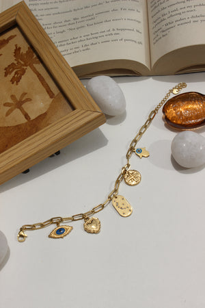 Whispershield Charms Bracelet with blue stones on a white surface with an open book and framed picture