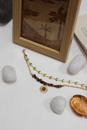Rootlight Layered Bracelet with a sun pendant on a white surface with stones and a wooden frame