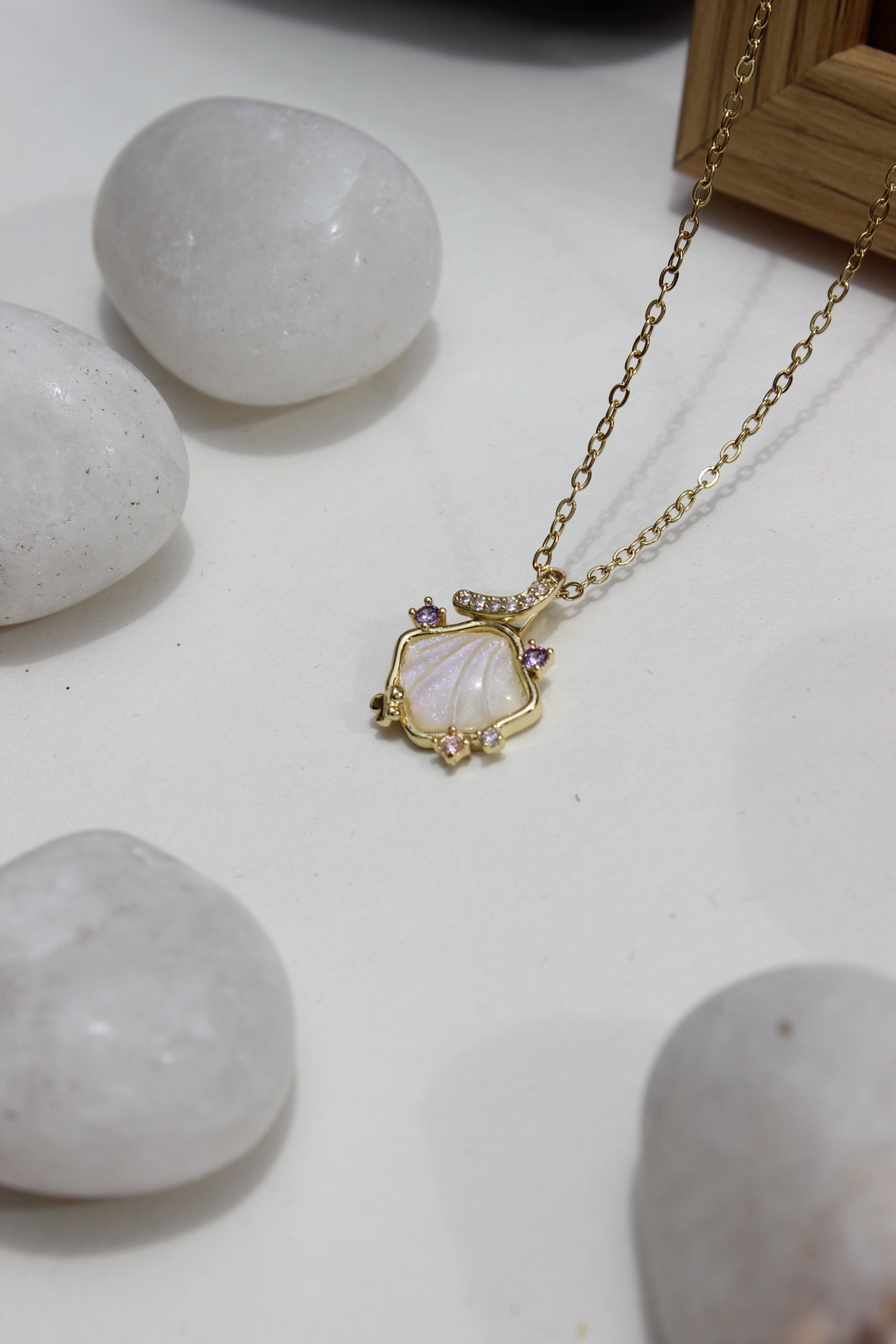 Heir to the Sea Pendant Necklace on a white surface with stones