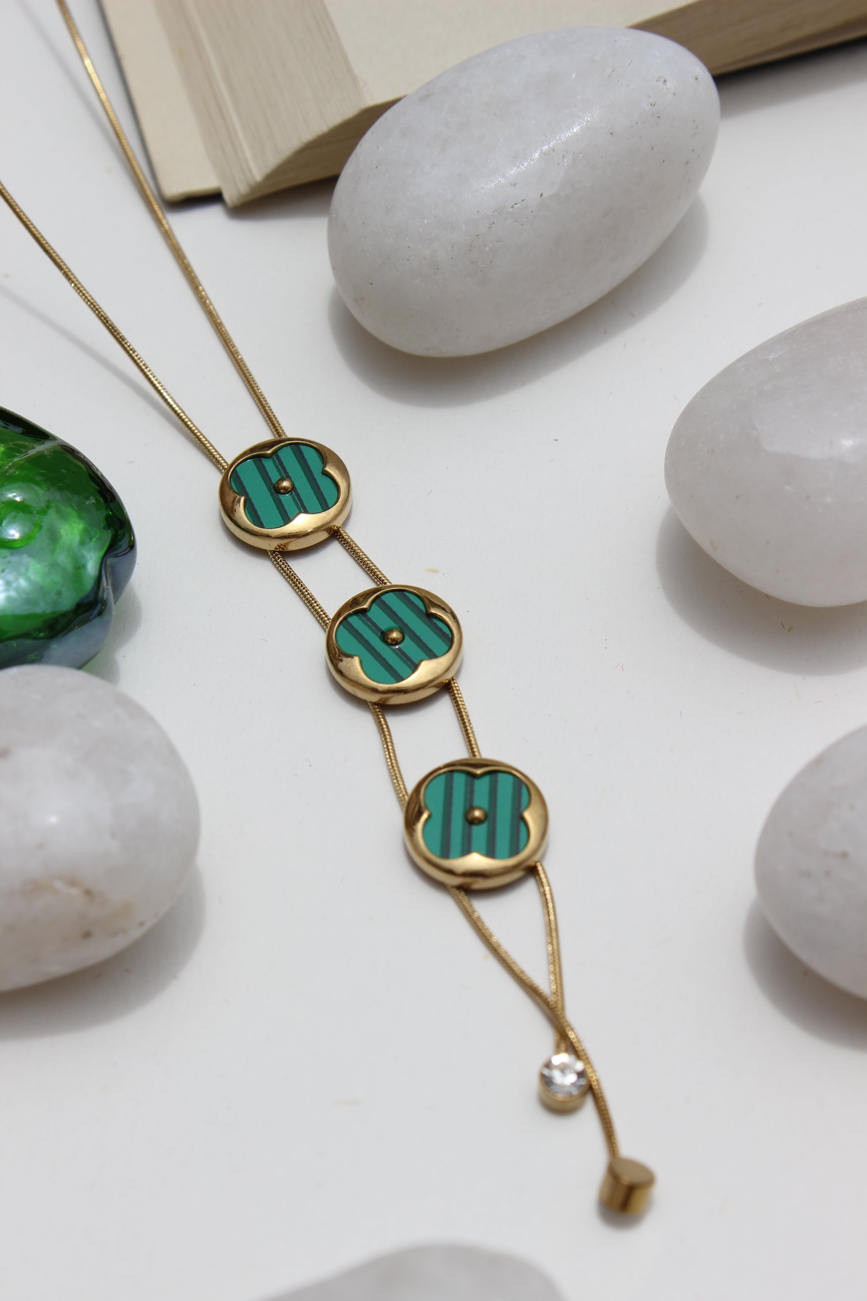 Green Mirage Necklace on a white surface with stones and seashell