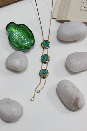 Green Mirage Necklace on a white surface with rocks