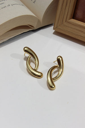 Lushline Earrings on a white surface with an open book in the background