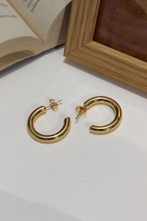 Sol Form Earrings on a white surface with a wooden box in the background