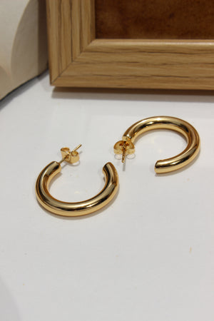 Sol Form Earrings on a white surface with a wooden frame in the background