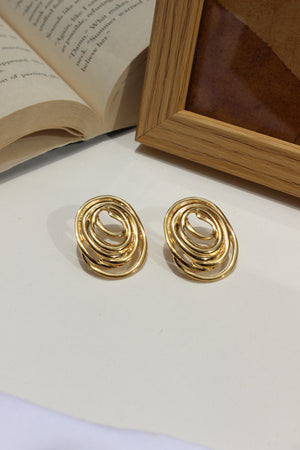 Gleamette Earrings on a white surface with a book and wooden frame in the background