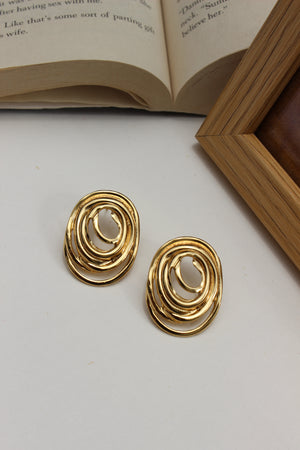 Gleamette Earrings on a white surface with an open book in the background