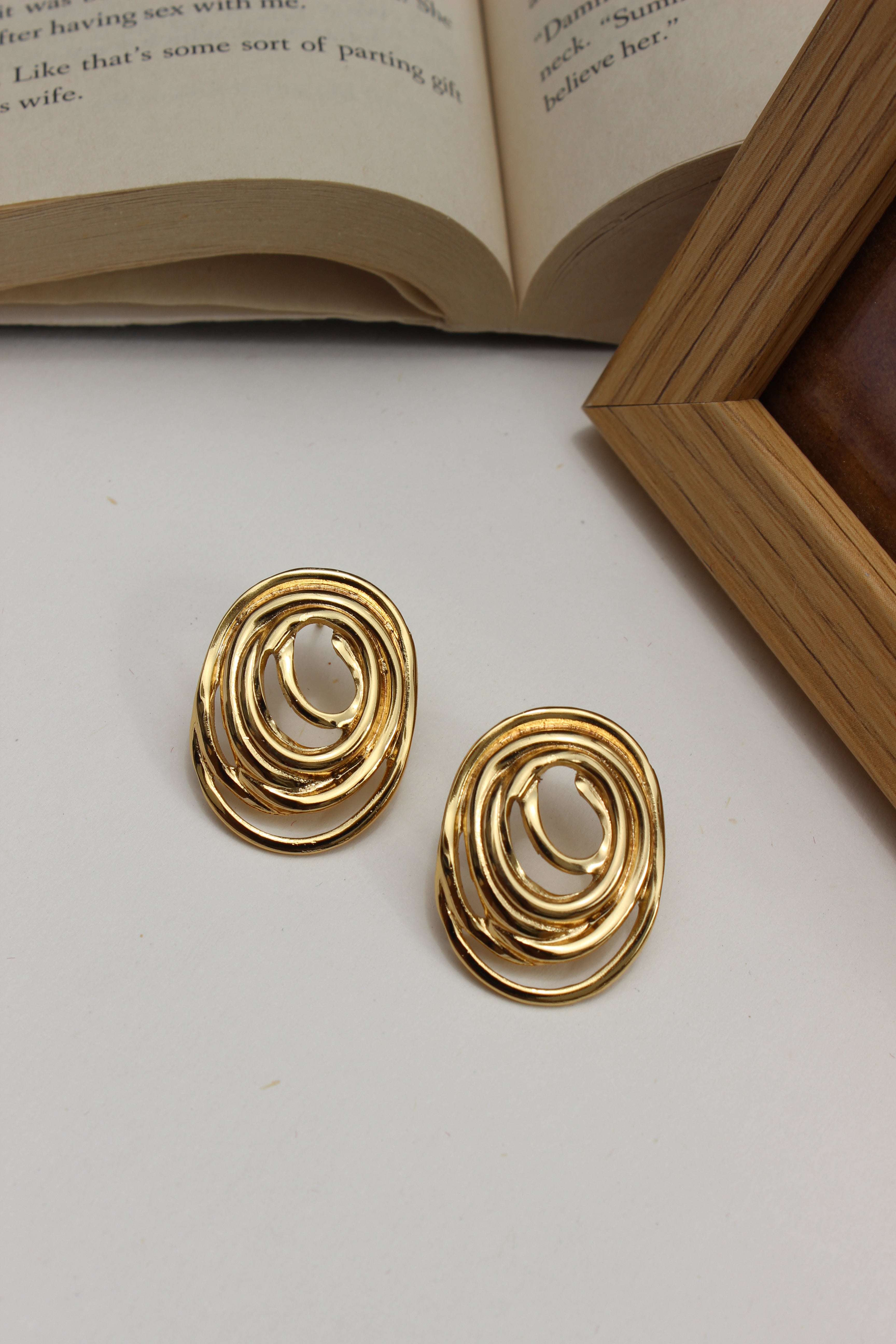 Gleamette Earrings on a white surface with an open book in the background