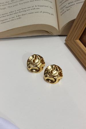 Musecore Stud Earrings on a white surface next to an open book