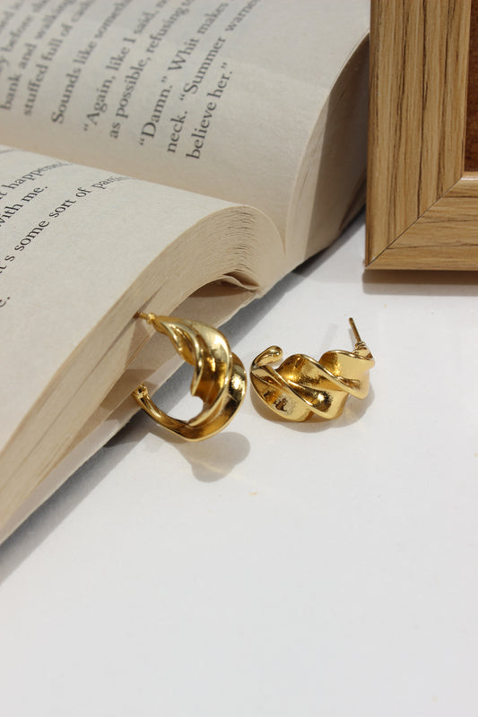 Sunspell Earrings on an open book with a wooden frame in the background