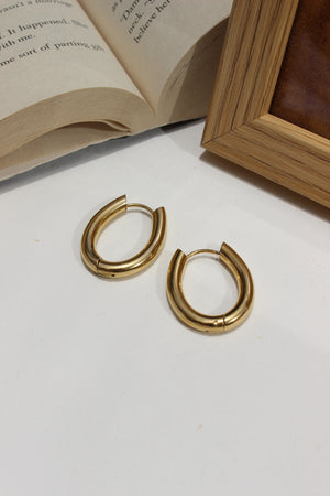 Aurume Earrings on a white surface with an open book and wooden box in the background