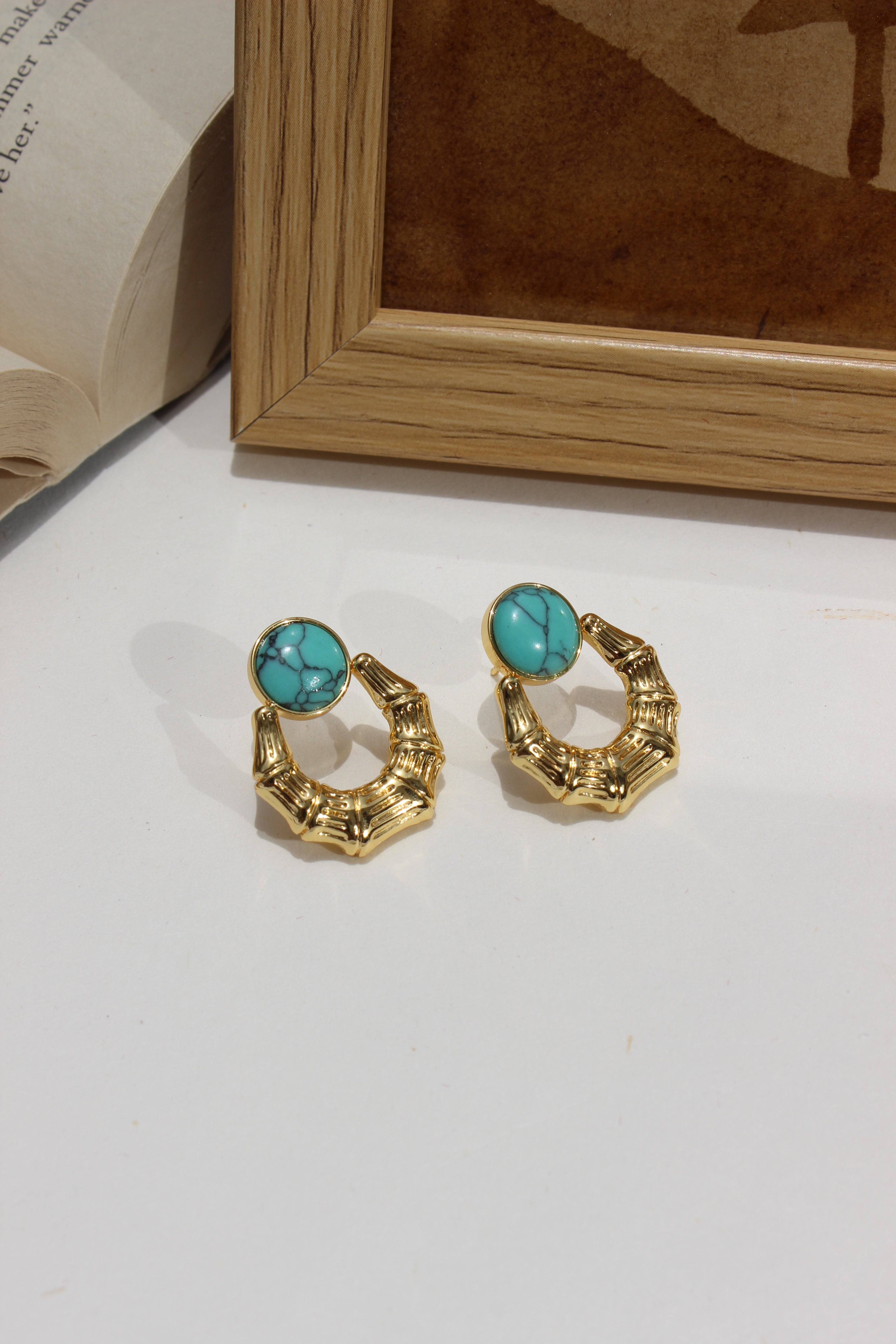 Azure Arc Earrings on a white surface next to a wooden frame