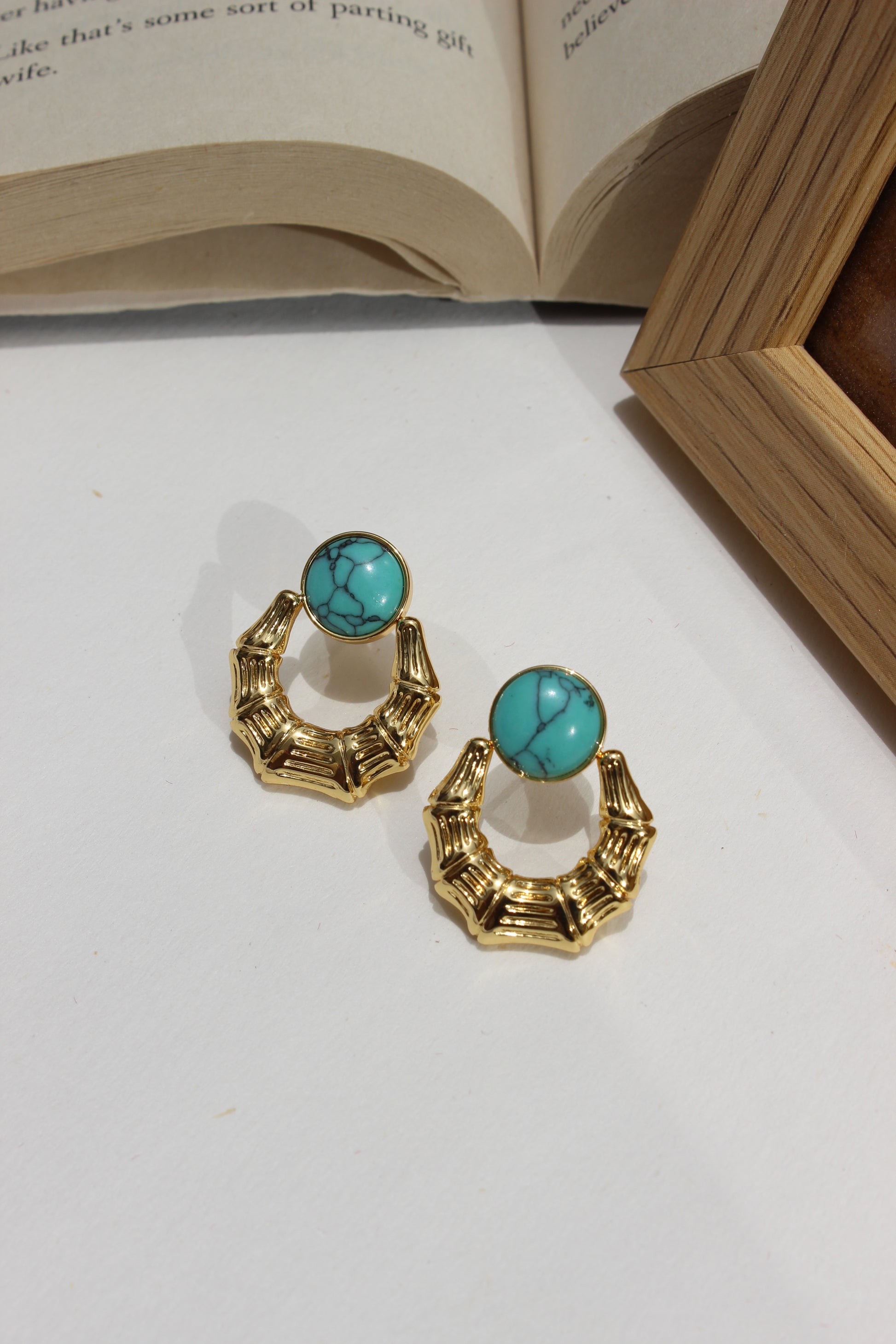 Azure Arc Earrings on a white surface next to an open book