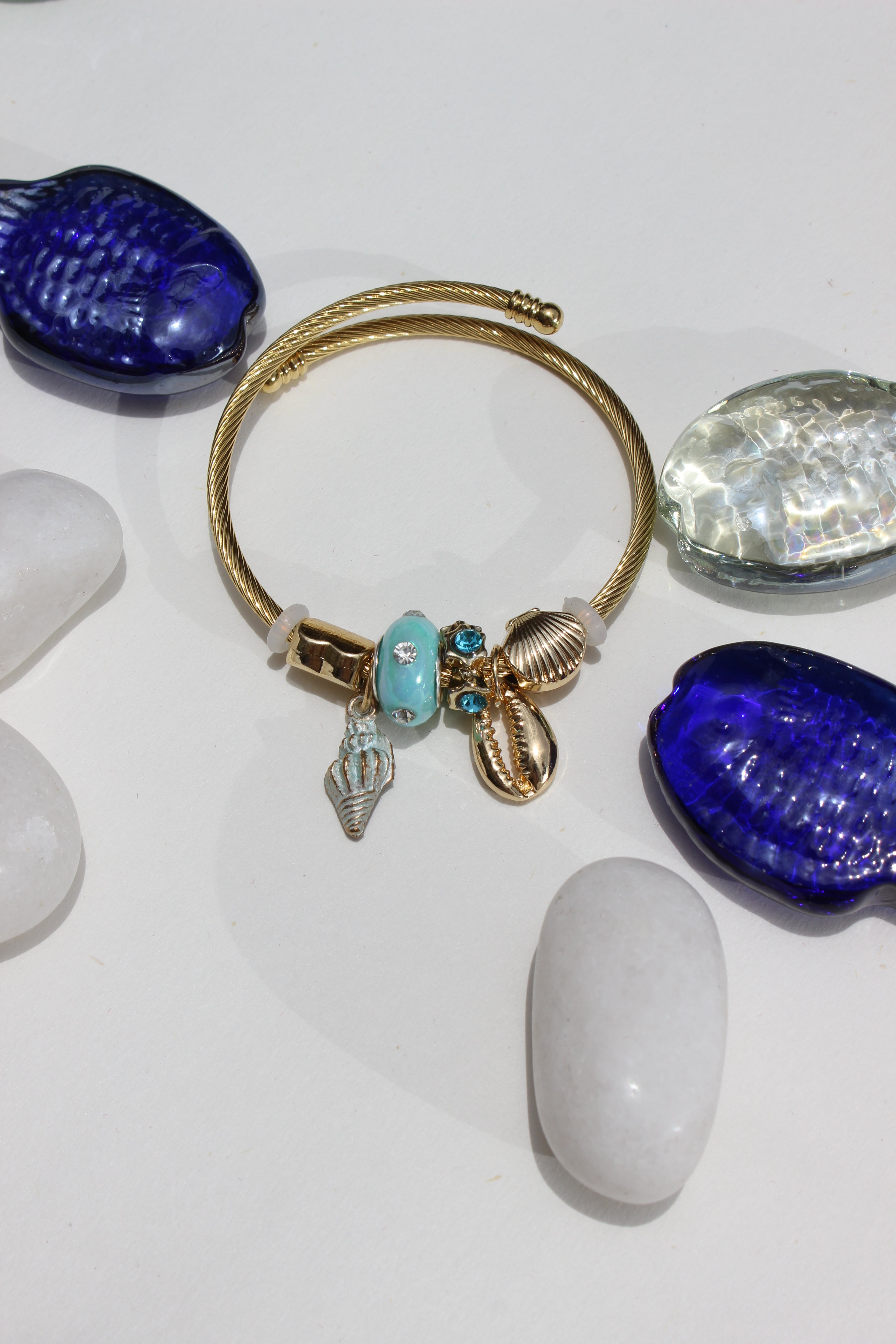 Celestide Charms Bracelet on a white background nearby stones and seashell