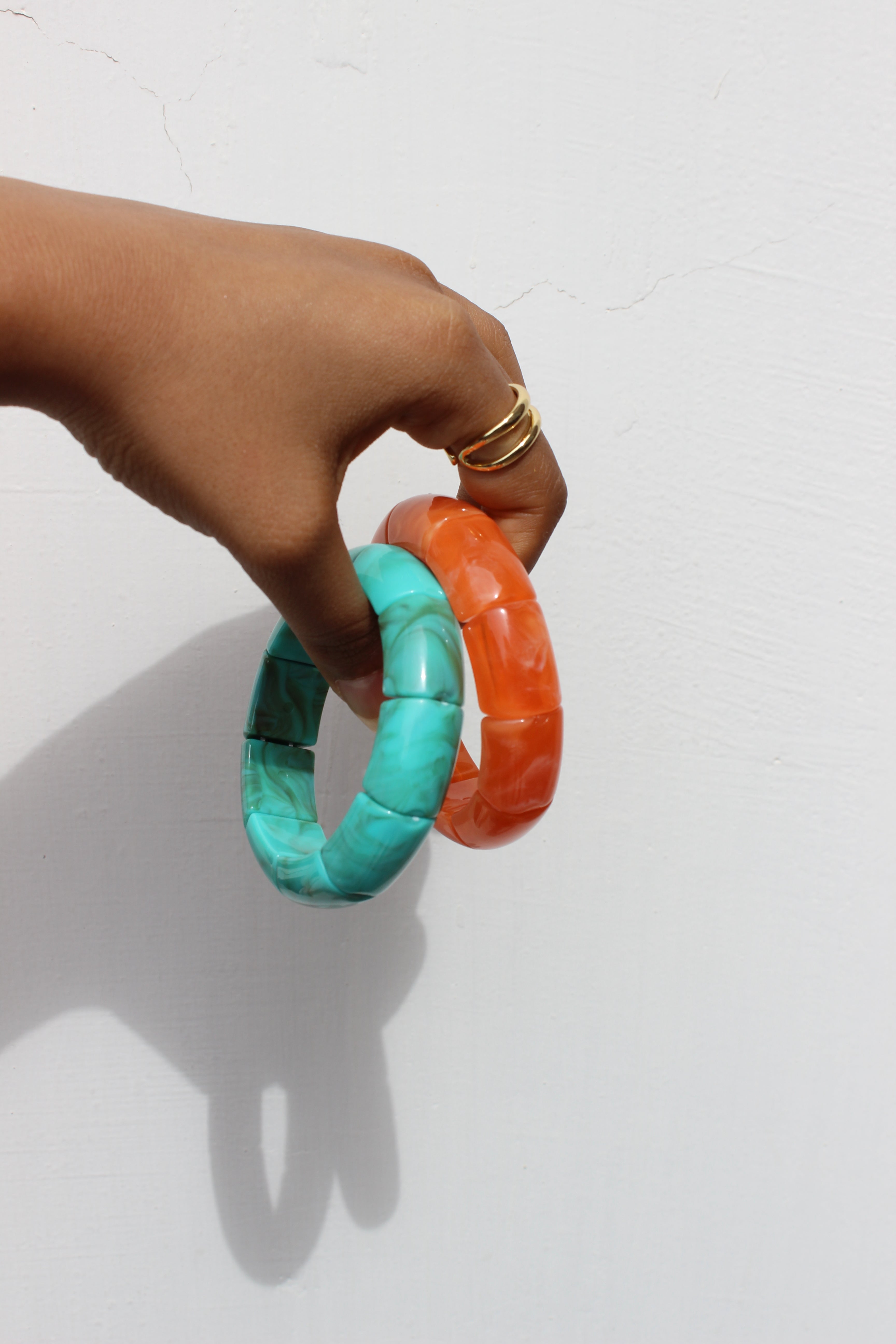 Hand holding Peach Orbit Bangle Bracelets against a white background