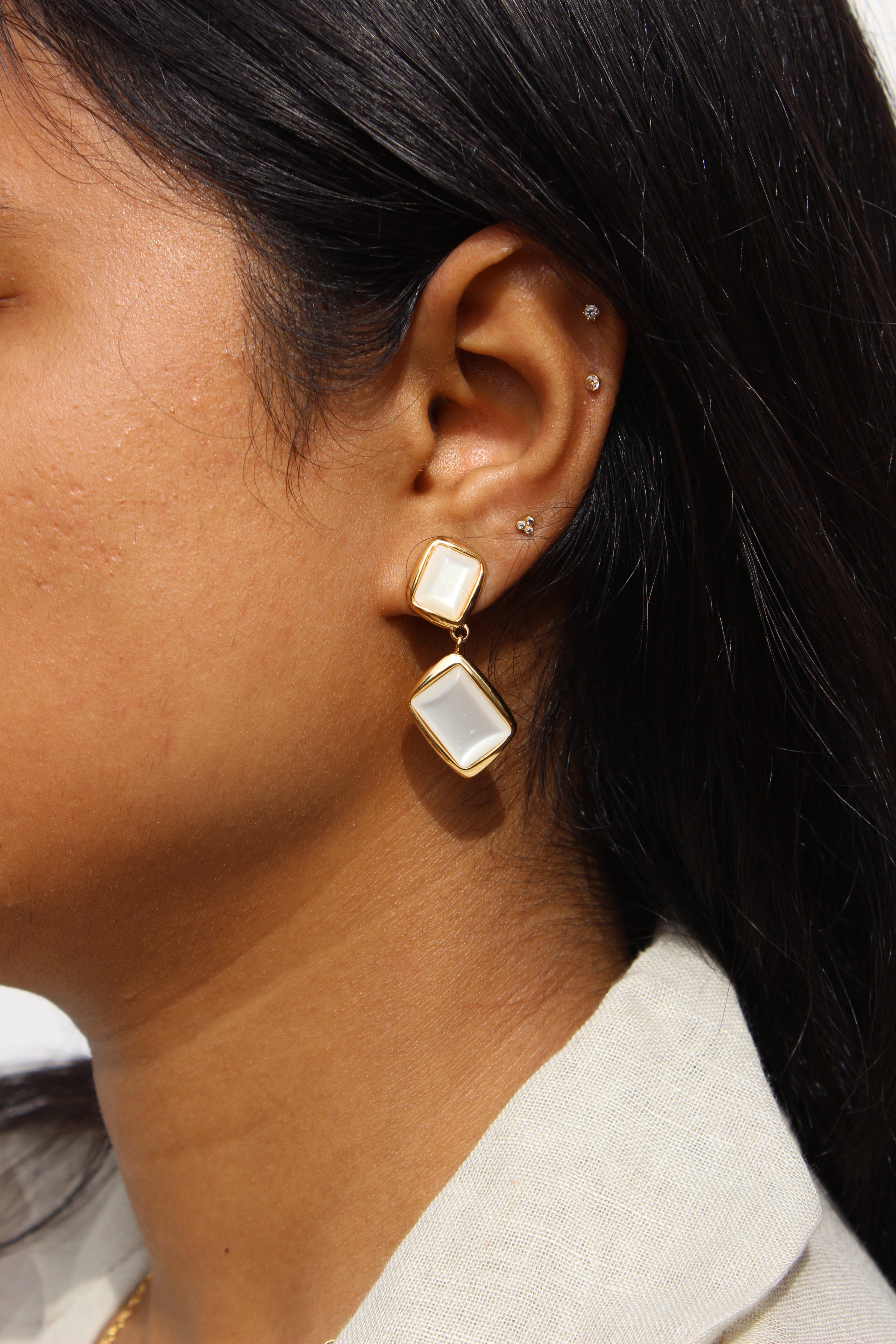 Close-up of an ear wearing a Ivory Drop Earrings with a white gemstone