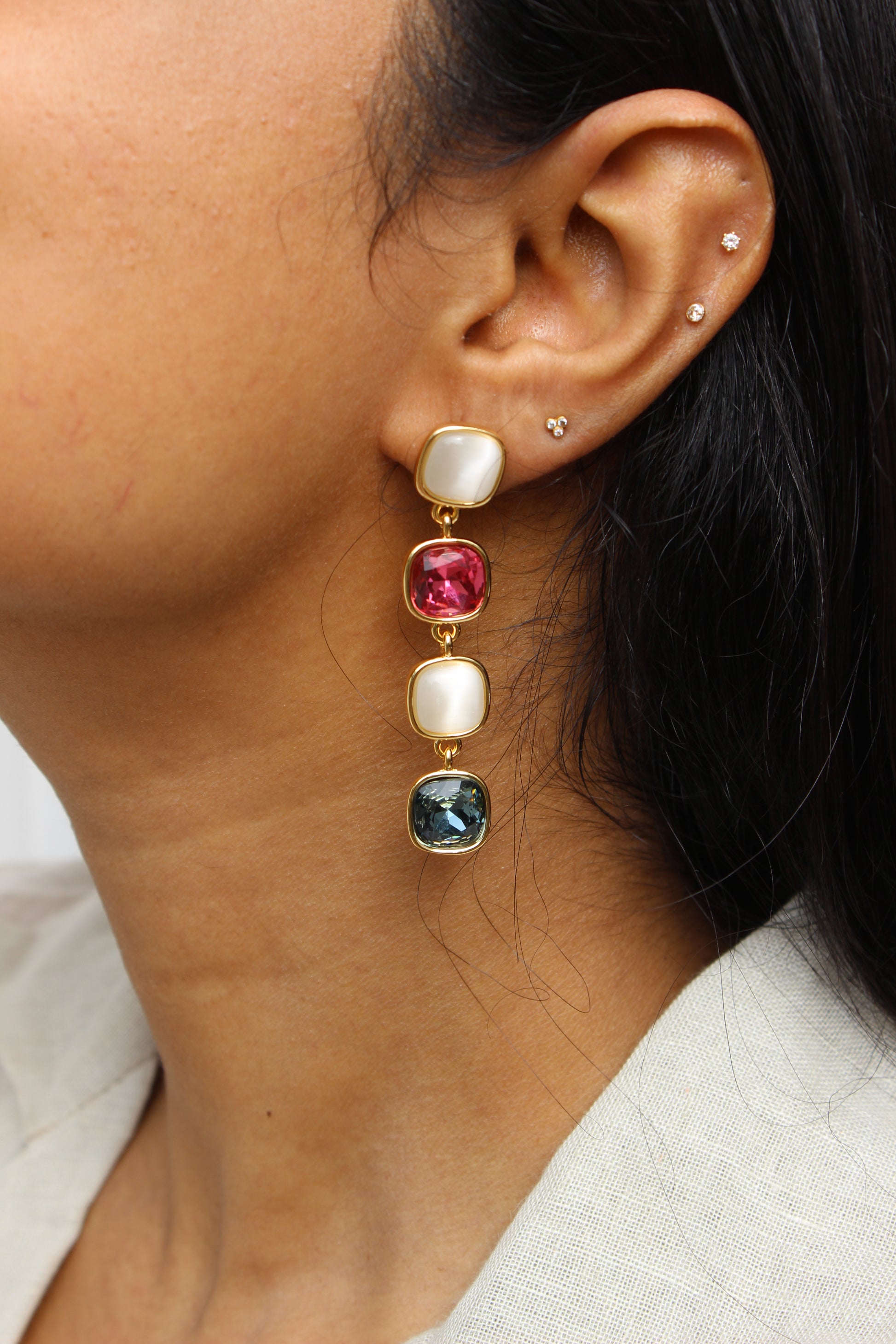 Close-up of an model wearing a Skyfire Gleam Earrings with colored  gemstones