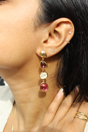 Close-up of an ear Ocean Glows Pink Earrings with red gemstones