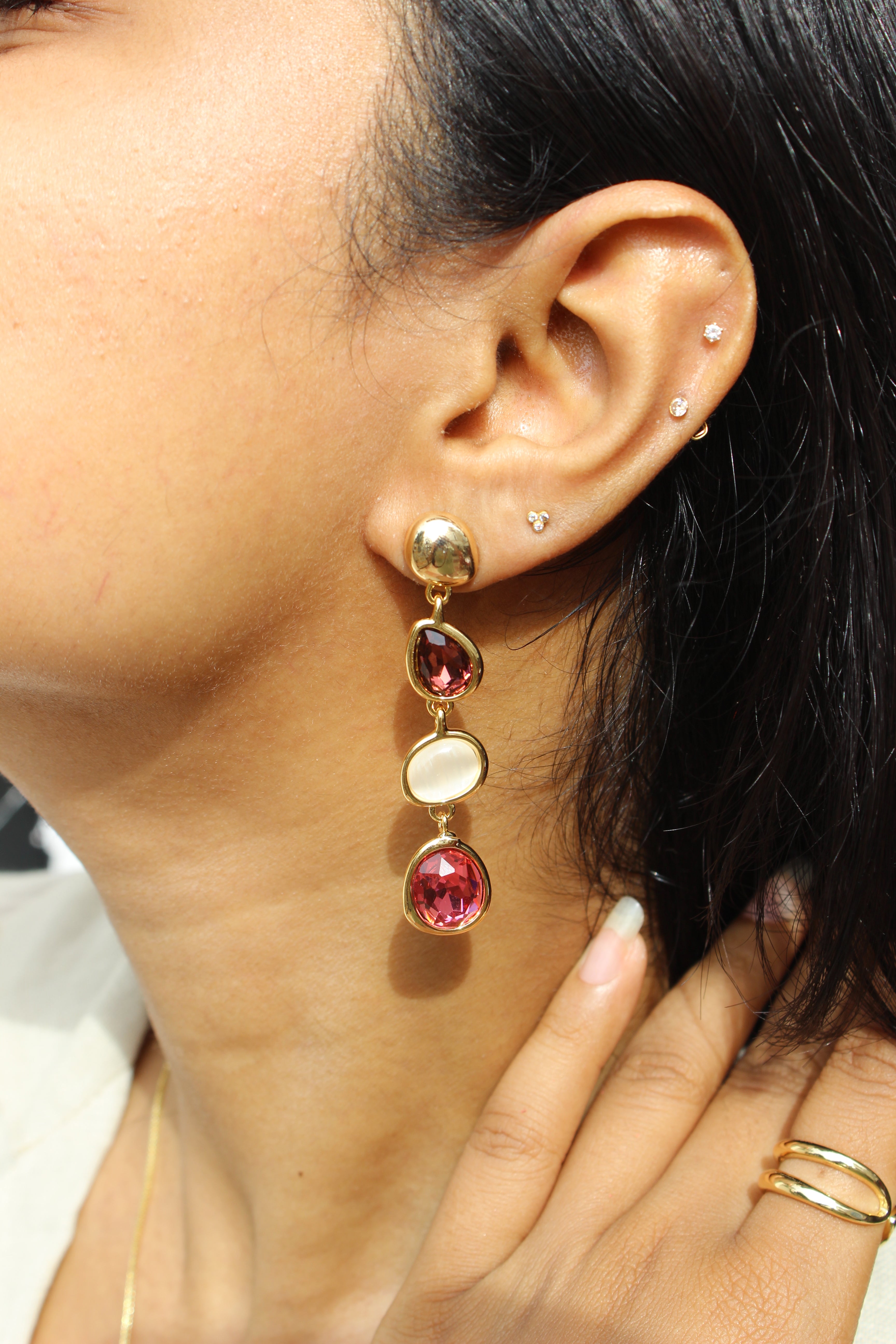 Close-up of an ear Ocean Glows Pink Earrings with red gemstones