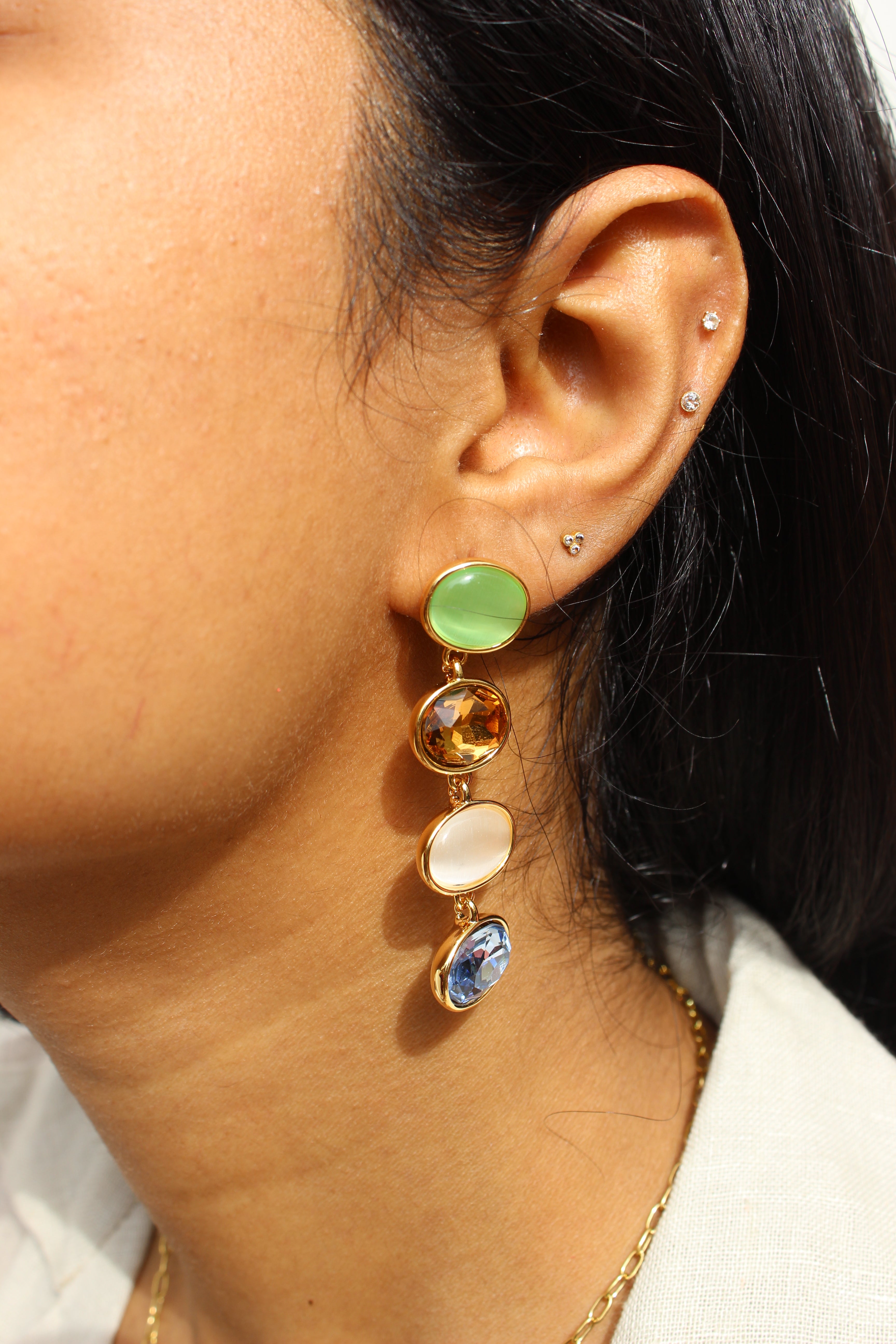 Close-up of an ear with a Gemstone Reverie Earrings featuring colored stones