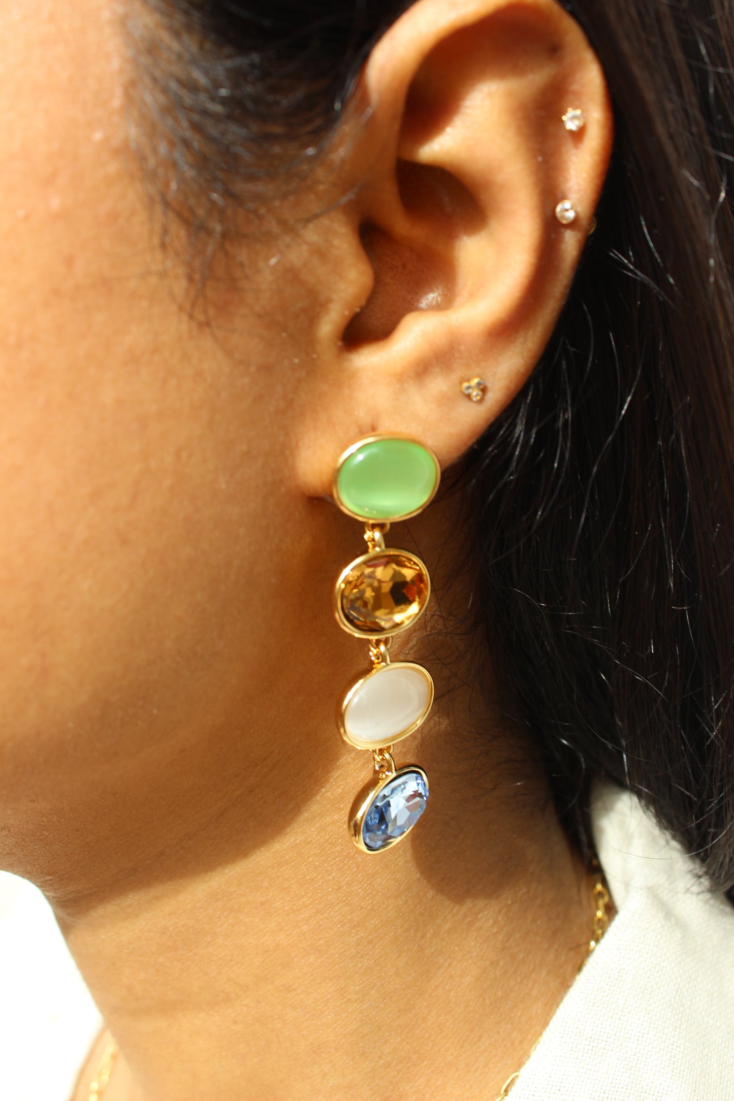 Close-up of an ear wearing a Gemstone Reverie Earrings with colored stones