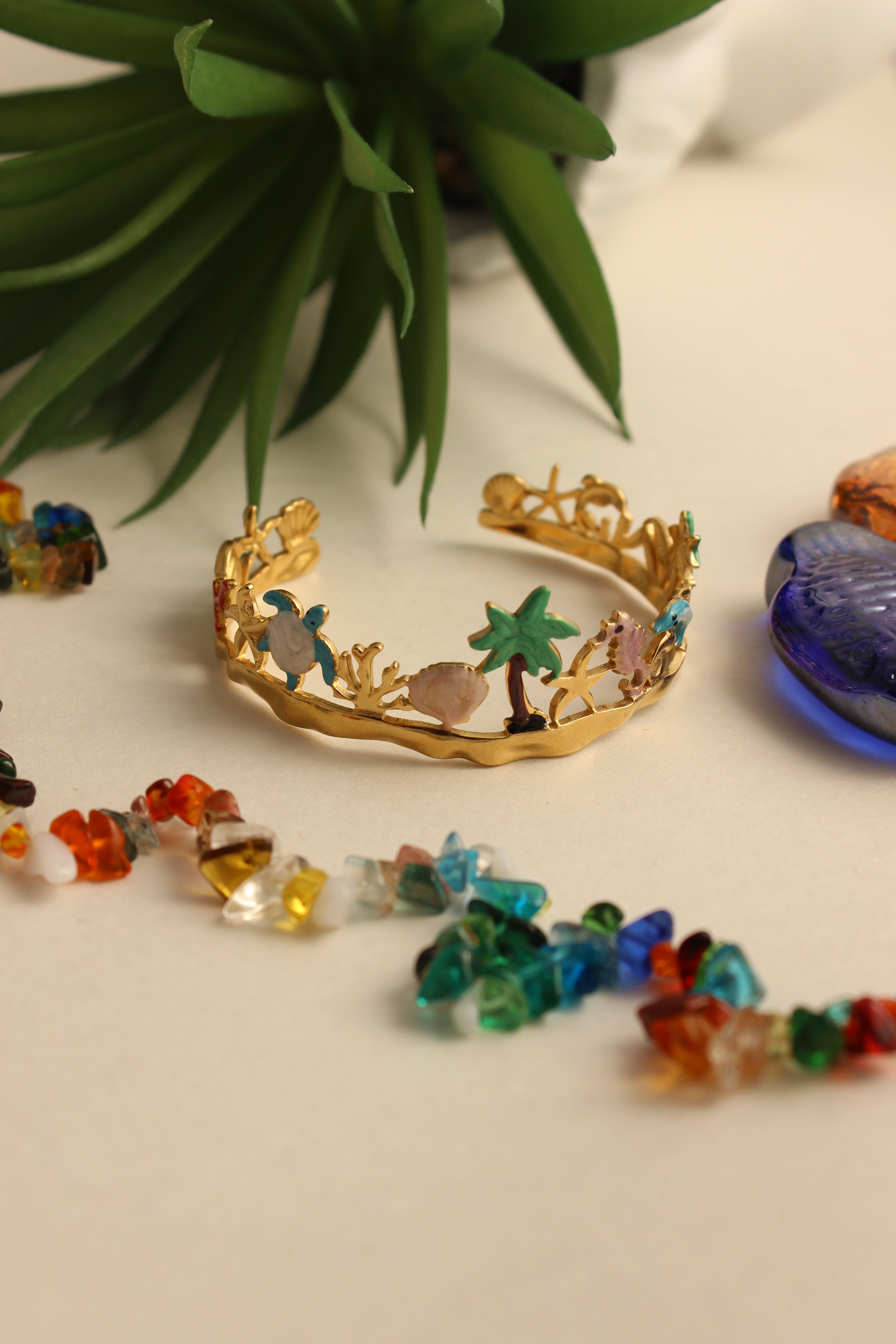 Lagoon Dream Cuff Bracelet on a white surface with a plant in the foreground