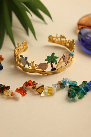 Lagoon Dream Cuff Bracelet with gold, green, blue, and multicolored beads on a beige background