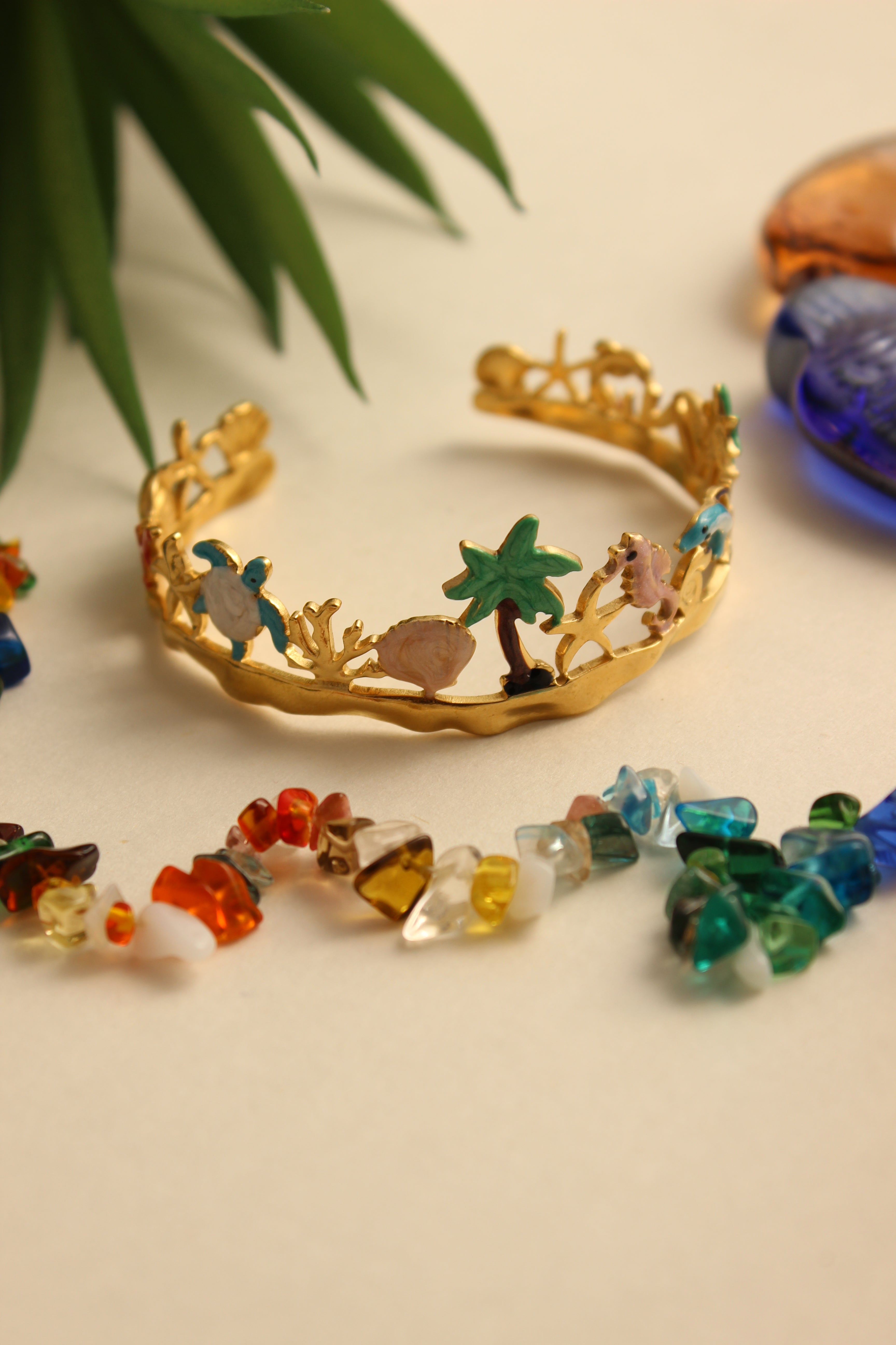 Lagoon Dream Cuff Bracelet with gold, green, blue, and multicolored beads on a beige background