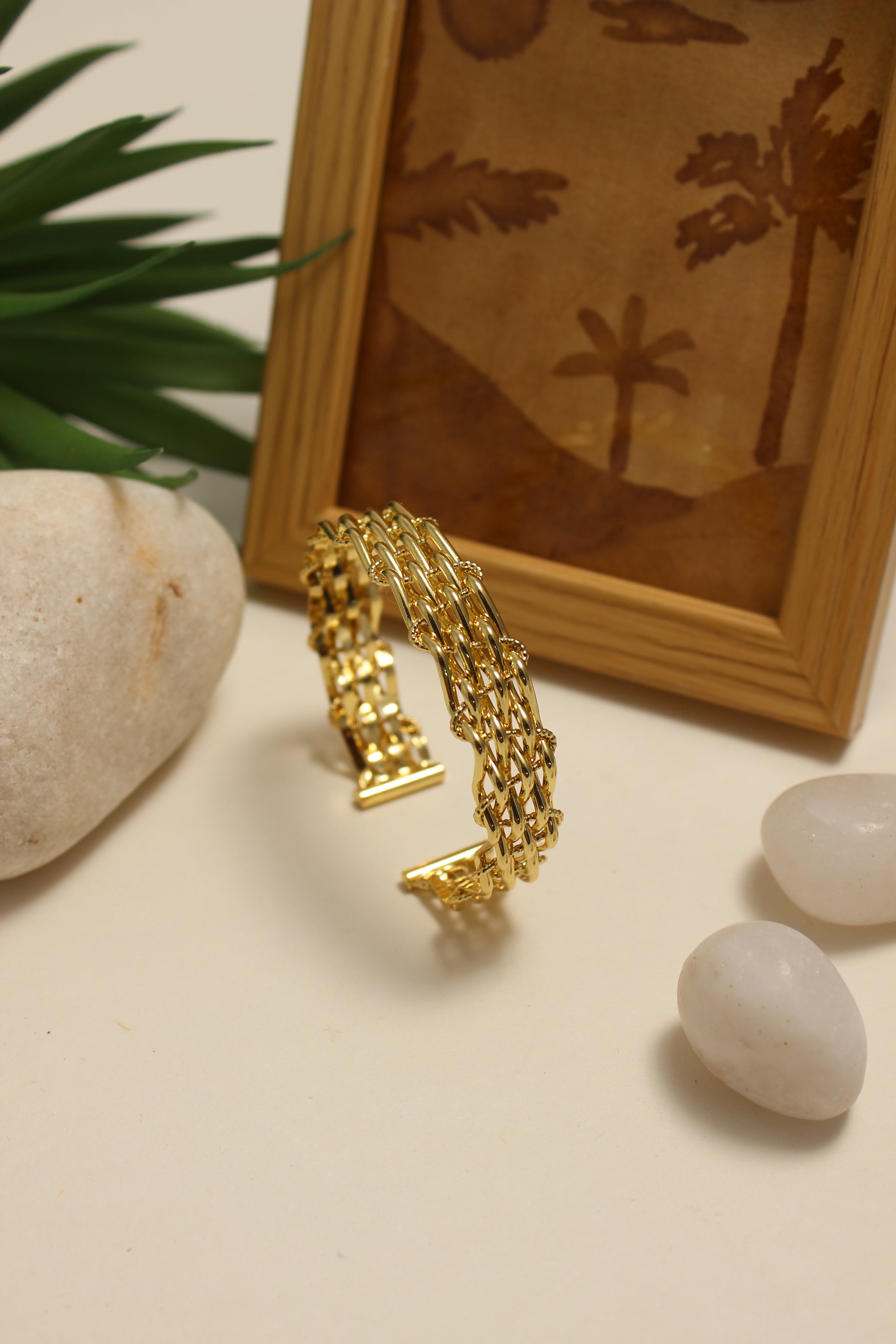 Legacy Cuff Bracelet on a neutral background with pebbles and a framed picture