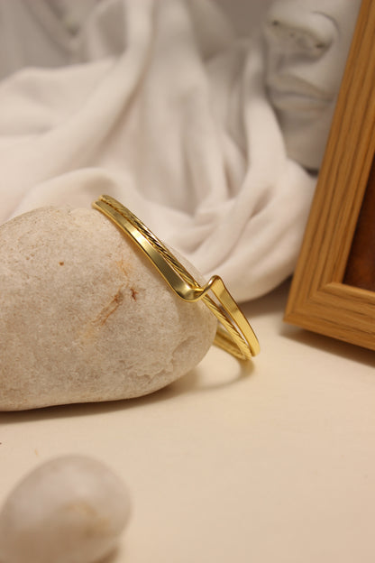 Ouro Cuff Bracelet on a stone surface with a soft background